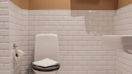 Home Hotel Baltzar - Deluxe Double: A clean bathroom with white subway tiles, a toilet, fresh towels, and a patterned floor.