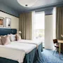 Et moderne hotelværelse på Hernö Gin Hotel med to komfortable senge, et skrivebord og et stort vindue med udsigt.