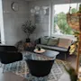 An inviting lounge space featuring comfortable seating, a coffee table, and lush greenery, with a bright window view.
