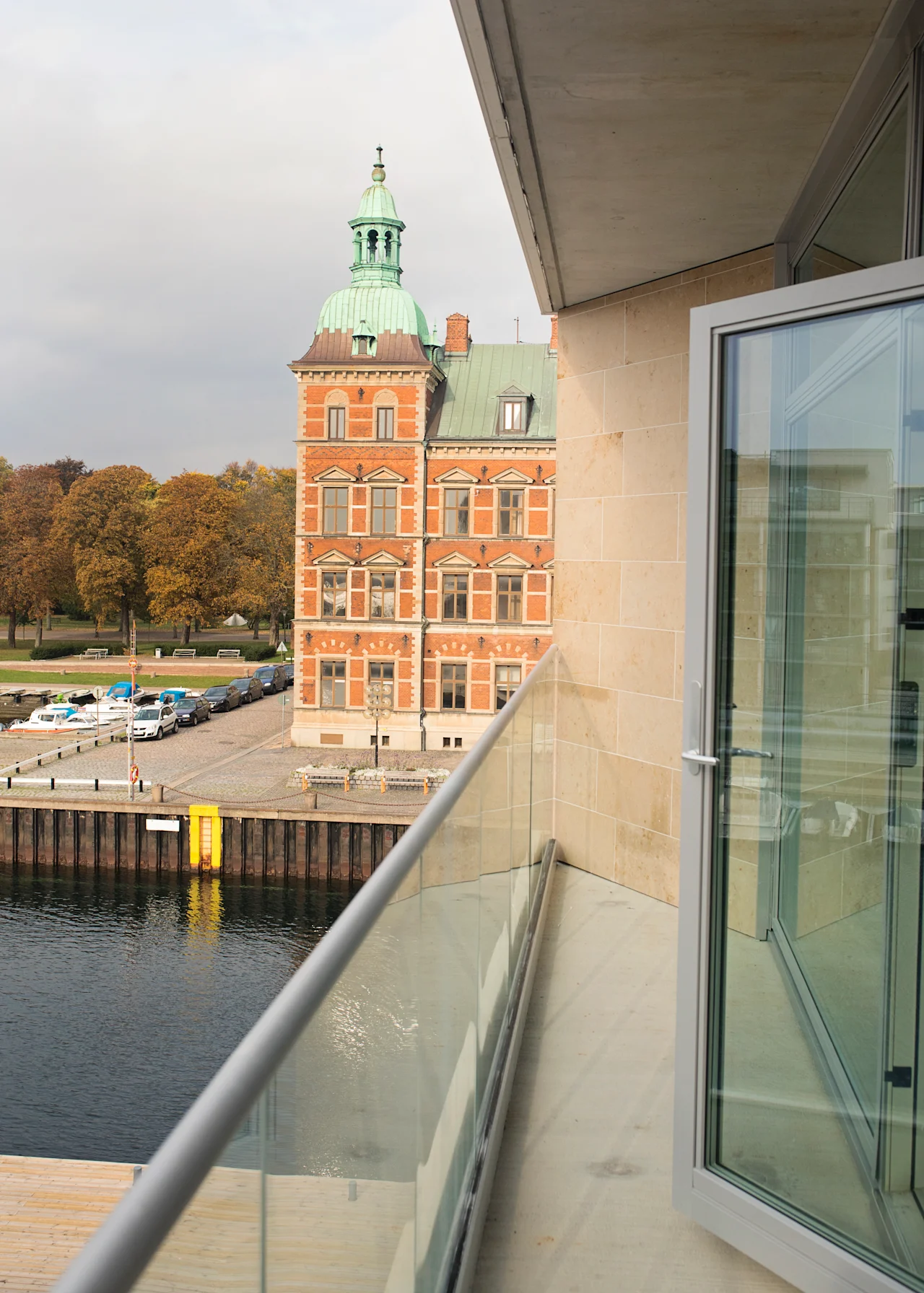 Kaunis näkymä parvekkeelta Quality Hotel Öresundissa, historiallinen rakennus vihreällä kupolilla, ranta ja katu.