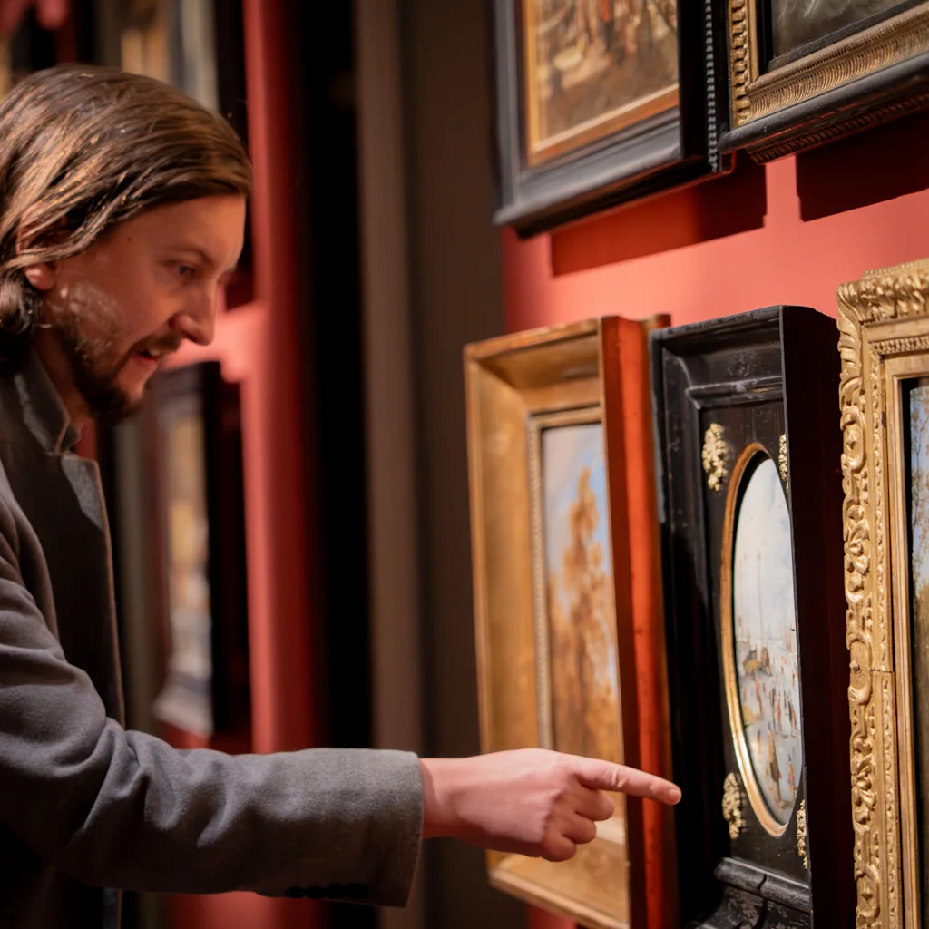 A person points at a framed painting in a gallery, engaging with the art on display.