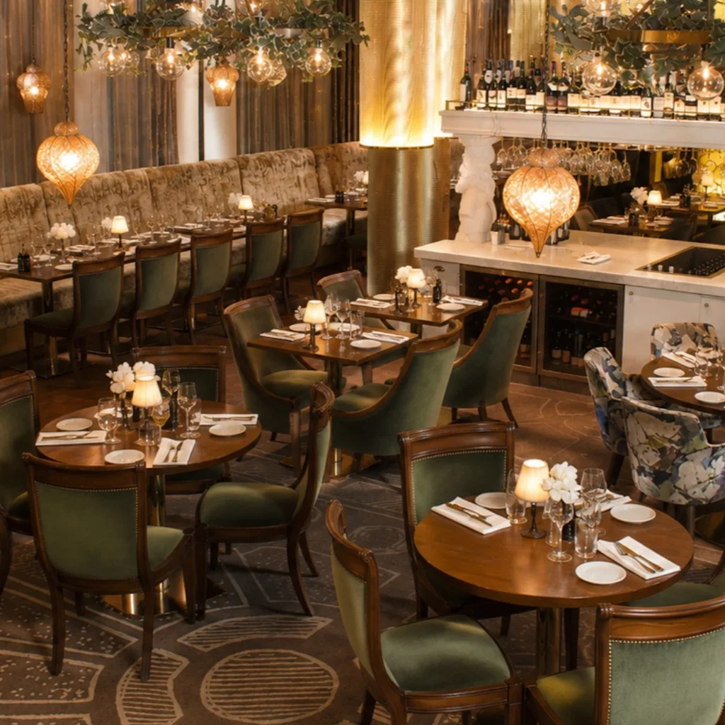 An elegant restaurant or bar interior with warm lighting, set tables, and a stylish bar area, creating an inviting atmosphere.