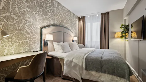 A well-appointed hotel room featuring a comfortable bed, a functional desk area, and soft lighting for a relaxing stay.