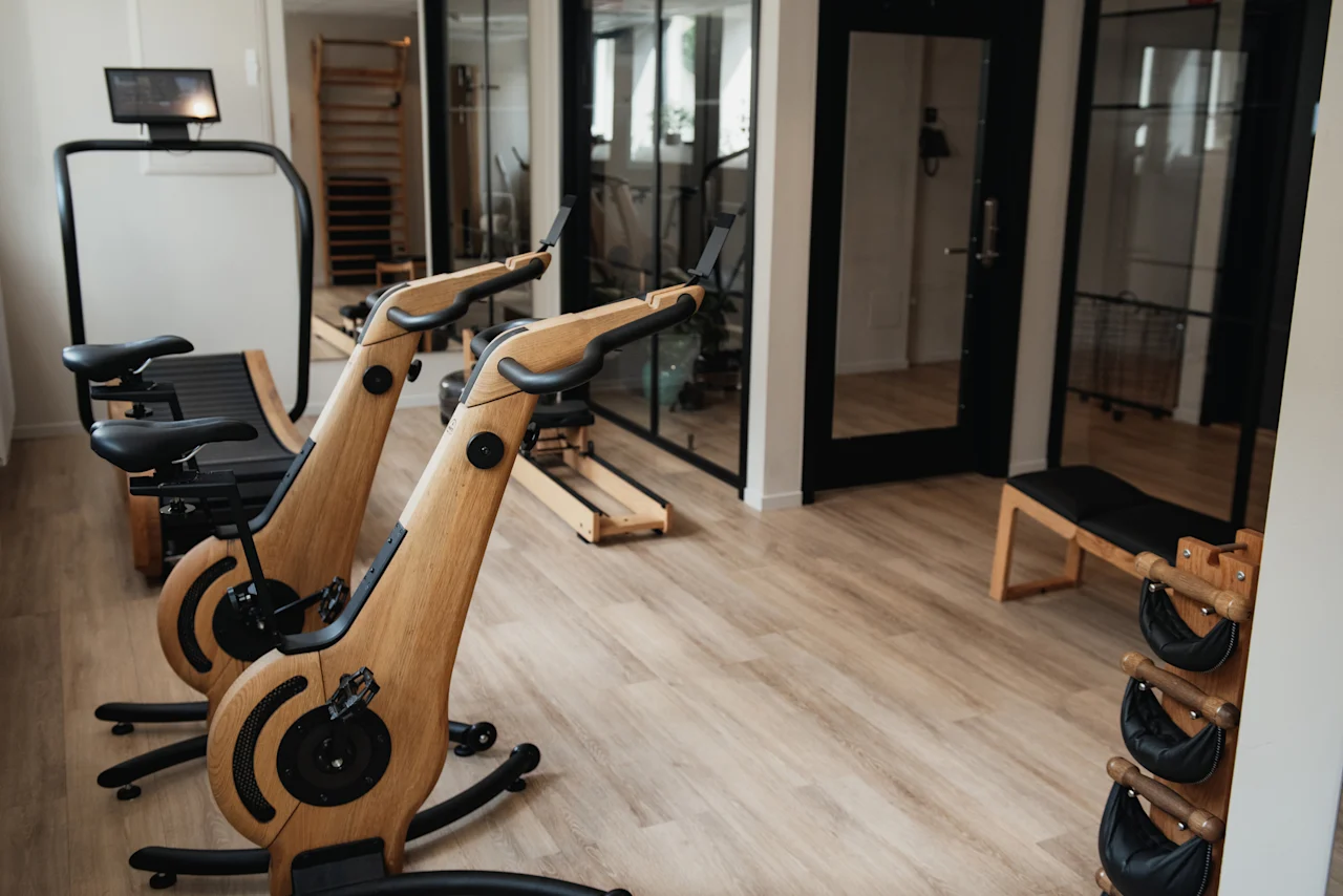 A modern fitness room with stylish wooden exercise bikes and other workout equipment at Home Hotel Uppsala.