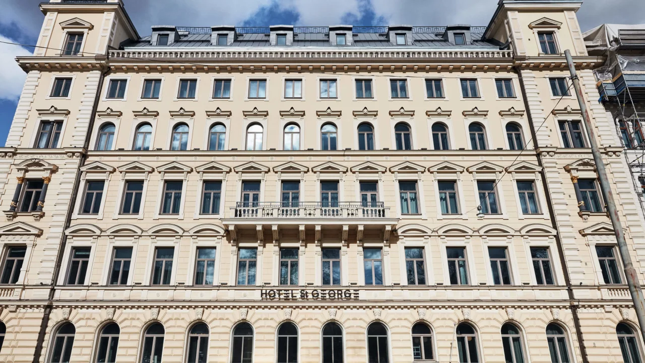 En nyklassicistisk byggnadsfasad under en blå himmel med en skylt "HOTEL ST GEORGE."