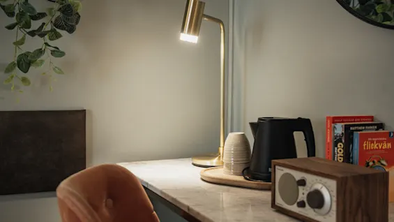 Et varmt og indbydende skrivebordsarrangement med en lampe, kedel og bøger. Tekst på bøger: FULLY REVISED AND UPDATED, GOLD, flickvan.