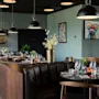 Et stilig restaurantinteriør med dekkede bord, komfortable båser og moderne kunst på veggene, som skaper en koselig spiseatmosfære.