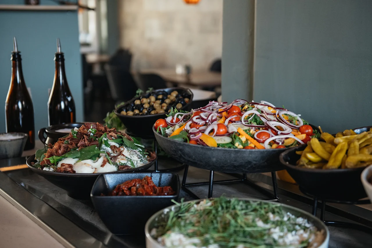 En livlig buffé på ett hotell, med fräscha sallader, oliver och andra läckra rätter redo för gästerna.