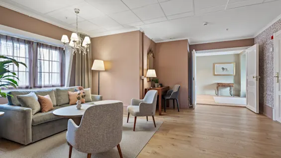 A cozy and elegant hotel lounge area with a comfortable sofa, armchairs, and a desk, inviting relaxation or work.