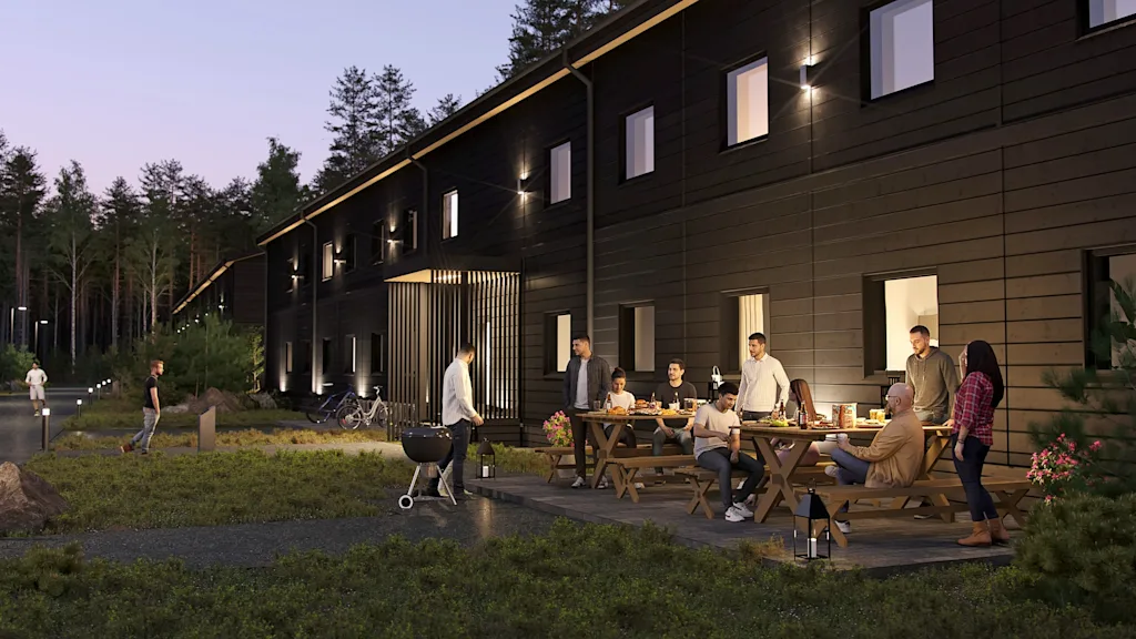 Folk nyter en kveldsgrilling og utendørs sammenkomst utenfor en moderne bygning omgitt av natur.