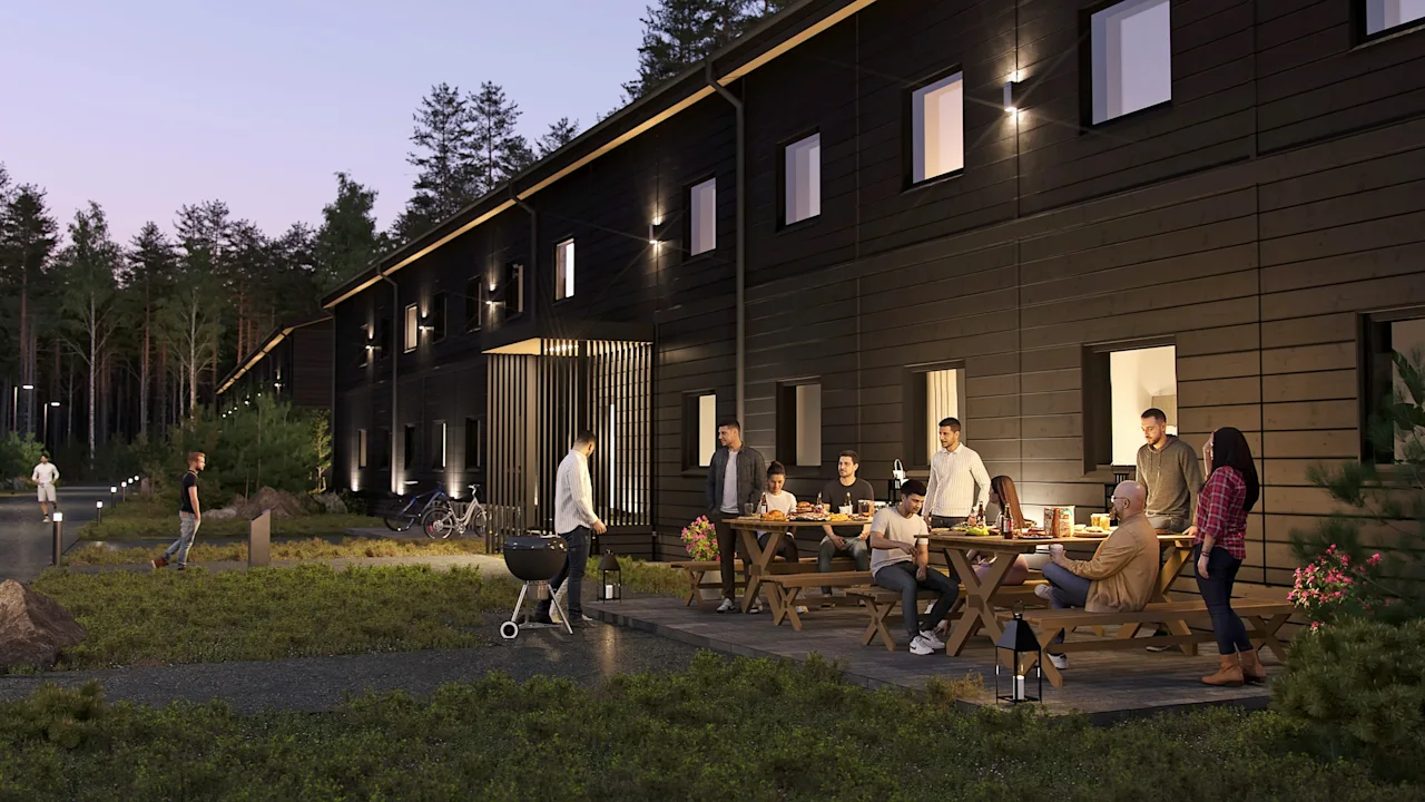 People enjoying an evening barbecue and outdoor gathering outside a modern building surrounded by nature.
