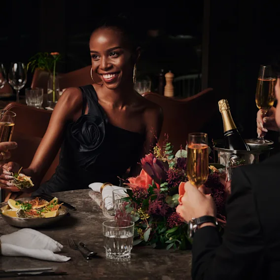 People raising a toast with champagne glasses during a festive dinner at a restaurant