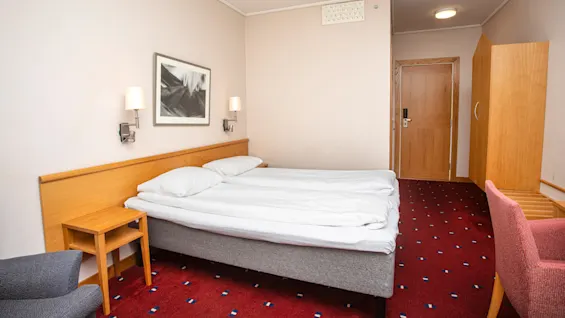 Standard doubleromm at Home Hotel Bryggen, with made bed and door.