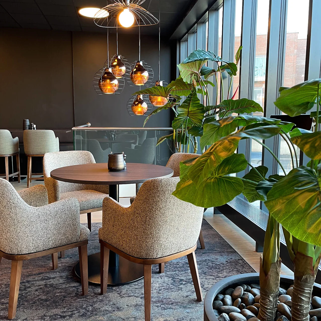 An indoor setting with contemporary furniture and decorative lighting near large windows.