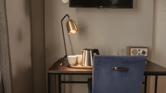 En mysig skrivbordsuppsättning i hotellrummet med en varm lampa, vattenkokare för varma drycker och en bekväm stol, perfekt för avkoppling.
