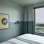 Ett mysigt rum på Stopover Hotel Falkenberg med en bekväm säng, ett fönster med utsikt och en unik väggkonst.