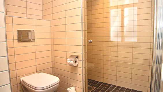 Ett rent och modernt badrum med toalett och en kaklad duschplats med glasvägg.