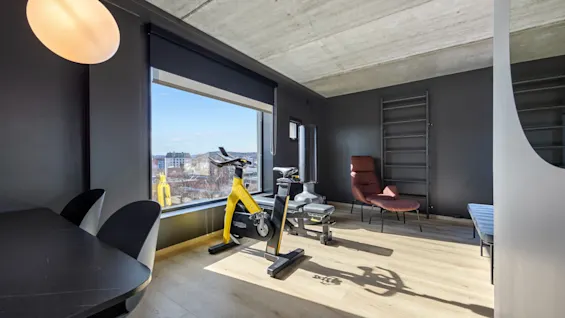 Sportssuite på Comfort Hotel Porsgrunn. Et moderne rom med treningsutstyr, spiseplass og stor vindusutsikt.