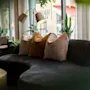 An inviting lounge area with a dark curved sofa, plush pillows, and warm lighting, perfect for relaxation.