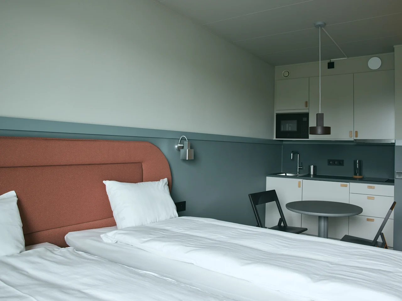 Ett modernt och funktionellt hotellrum på Stopover Hotel Falkenberg med en bekväm säng och ett kompakt pentry.