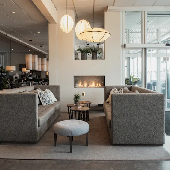A modern and inviting hotel lobby with comfortable sofas, a cozy fireplace, and stylish lighting.