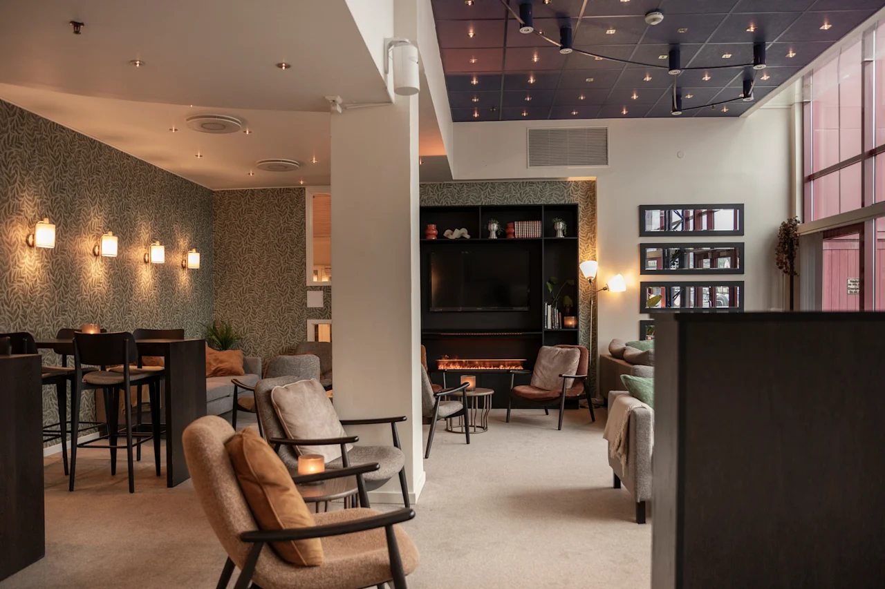 Viihtyisä hotellilounge, jossa on erilaisia istuinalueita, takka ja lämmin valaistus, täydellinen rentoutumiseen.