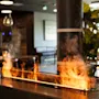 En moderne innendørspeis med dansende flammer og røyk, som skaper en varm og innbydende atmosfære i et stilig interiør.