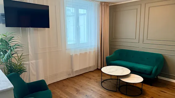 Viihtyisä hotellin juniorsviitti: vihreä sohva, nojatuoli, sohvapöydät ja seinä-TV. Junior Suite, Comfort Hotel Linköping City.