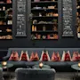 Et hyggeligt loungeområde med en sofa, lænestole og bogreoler. Tavler viser drinkmenuer med teksten BUBBEL enjoy ROTT VIN ROSE CIDER cheers.