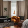 Et innbydende hotellrom med et komfortabelt salongområde, komplett med en sofa, to lenestoler og myk belysning.