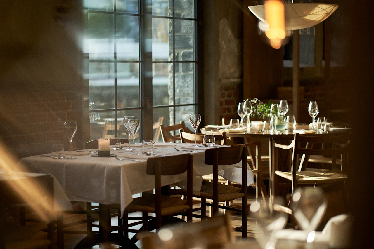 Et varmt og indbydende spiseområde på Sjøbua ved Hotel Brosundet i Ålesund, med dækkede borde og blød belysning.