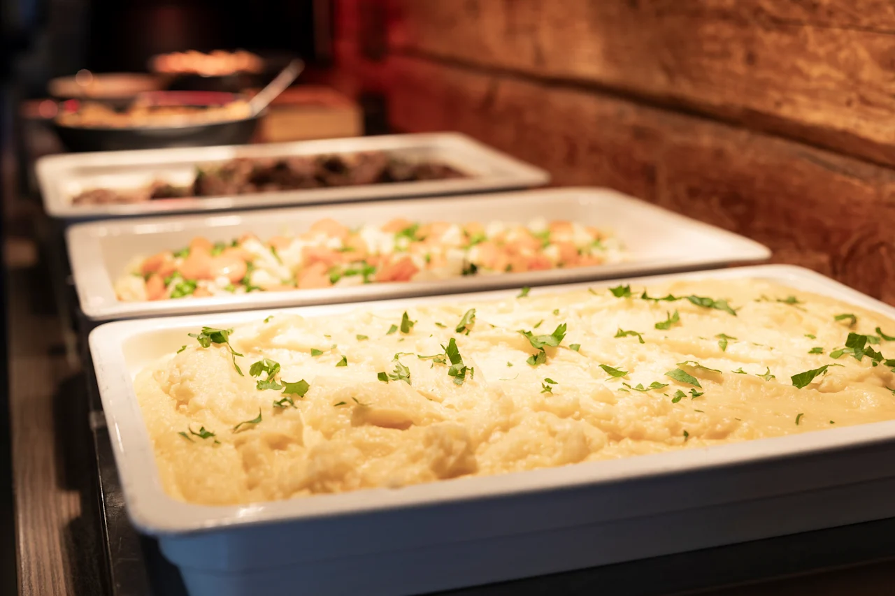 En varm og indbydende buffet med cremet kartoffelmos og andre lækre retter, klar til servering.