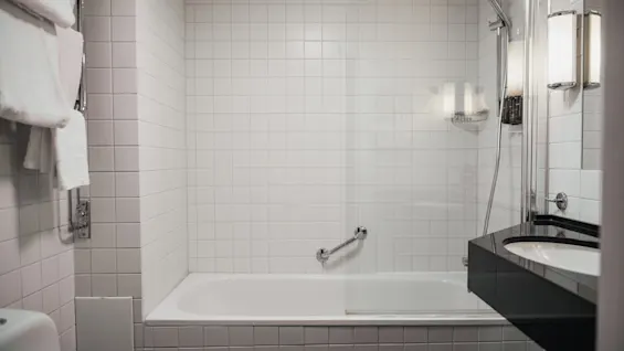 Et pletfrit badeværelse på Home Hotel Wellington, med et afslappende badekar og bruseområde, suppleret med en elegant håndvask.