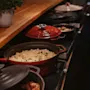 A cozy buffet setup at Home Hotel Uppsala, offering a selection of hot dishes in cast iron pots, including creamy mashed potatoes.