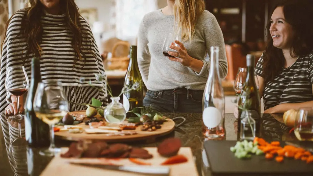 Friends cooking food and tasting wine together.