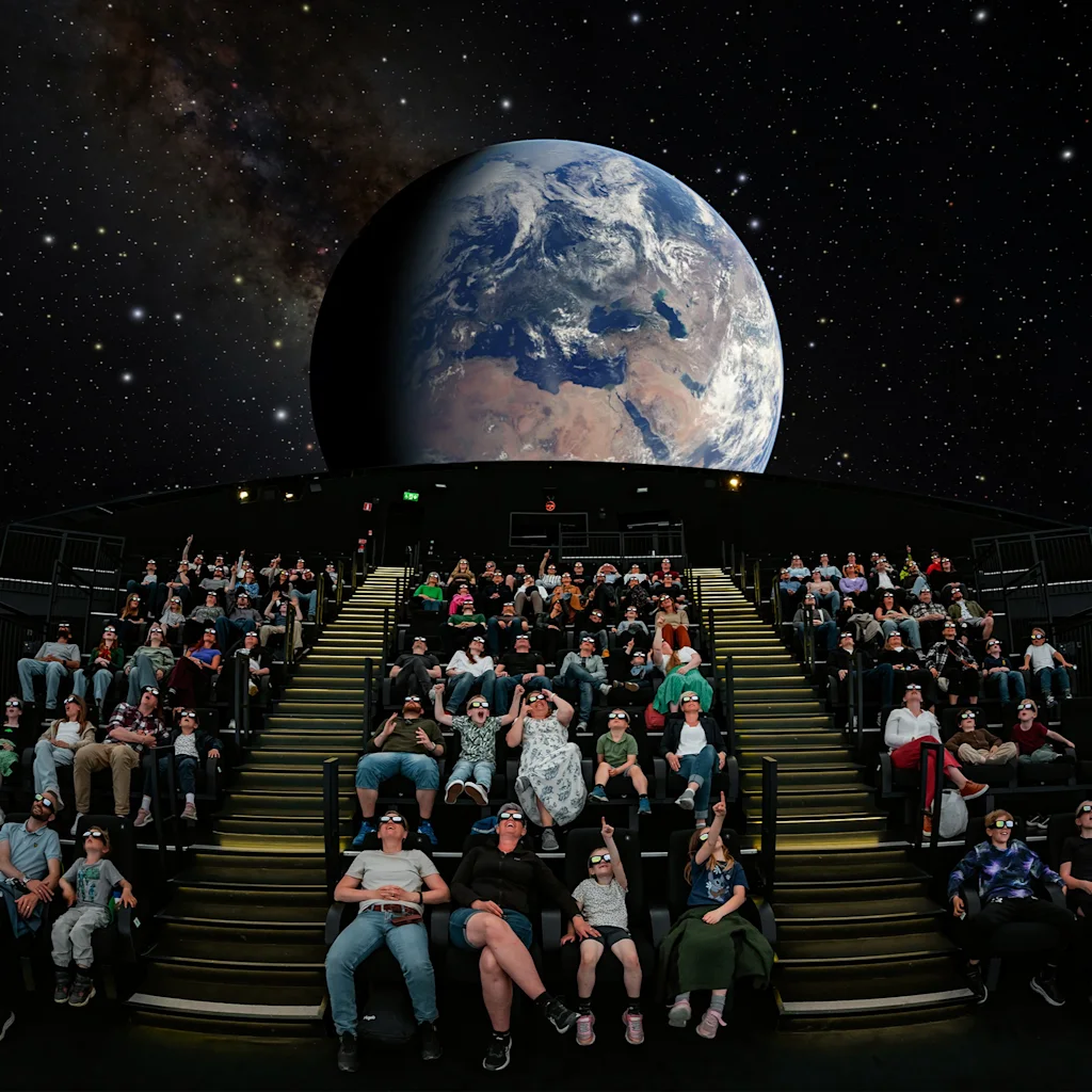 Yleisö planetaariossa katselemassa esitystä maapallosta ja tähtitaivaasta.