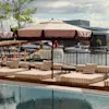 Ett poolområde med solstolar och parasoller med utsikt över en marina med båtar, vilket antyder en avkopplande utomhusmiljö.