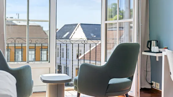 Two armchairs by a large window with an urban view, bright daylight.