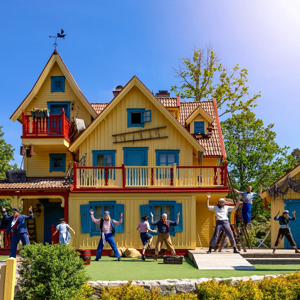 Performers in costumes act out a lively scene in front of Villa Villekulla at Astrid Lindgrens Värld in Vimmerby.