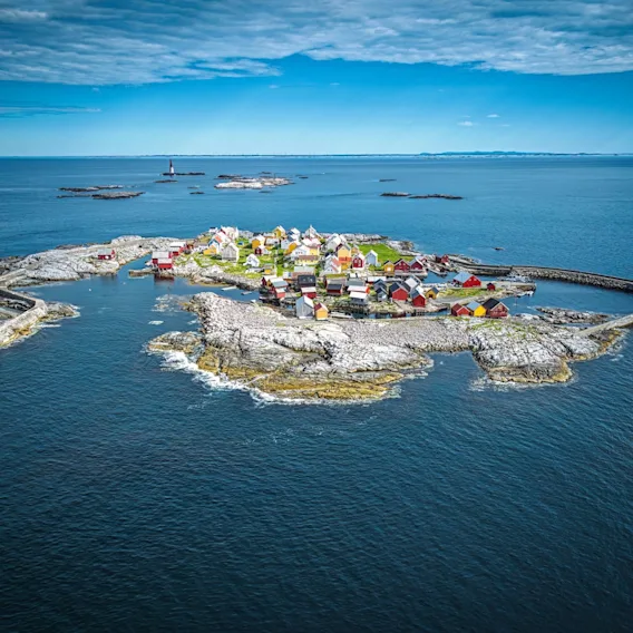 Luftfoto av den lille øya Grip med fargerike trehus omgitt av det åpne havet.