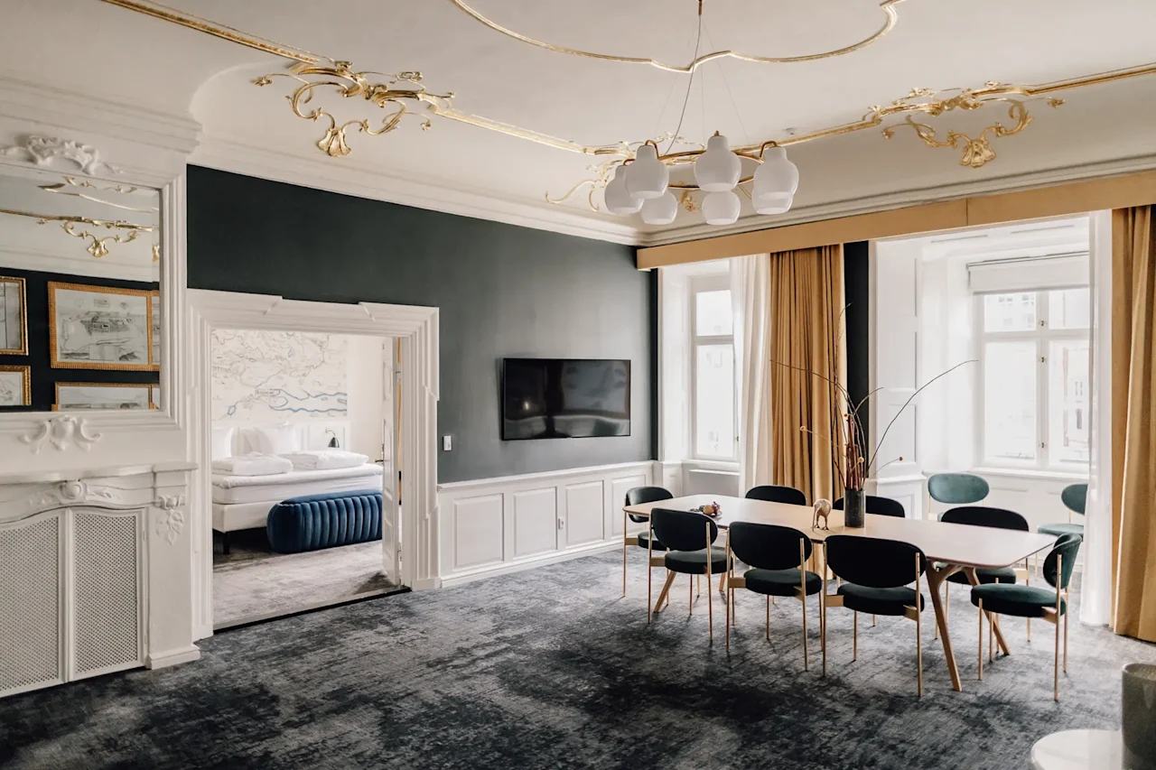 En luksuriøs hotelsuite med spiseplads og udsigt til et soveværelse, med elegant indretning og moderne møbler.