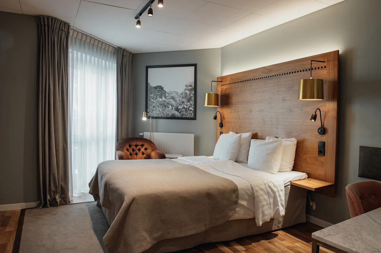 Et koselig hotellrom med en stor seng, sengegavl i tre og varm belysning, som inviterer til et komfortabelt opphold.