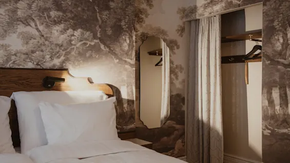 Home Hotel Baltzar - Superior Room. A cozy room with a comfortable bed, nature-inspired wallpaper, and an open closet area.