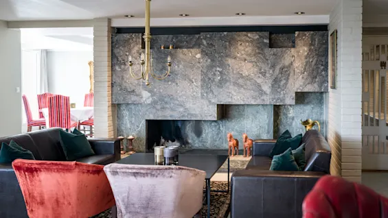 En stilig hotellounge med komfortable sitteplasser, en moderne peis og et glimt av et spiseområde.