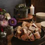 En varm og innbydende anretning med kakestykker, tallerkener, friske blomster og et tent lys.