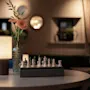 A cozy corner at Home Hotel Grand Bodø with a chess set ready for a game, illuminated by a warm lamp and fresh flowers.