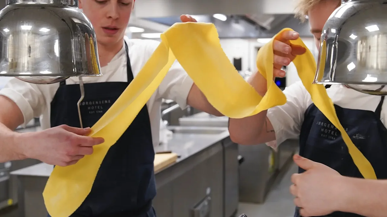 To kokker lager fersk pasta med en pastamaskin på et profesjonelt kjøkken ved Jørgensens Hotel – Restaurant Eydes.
