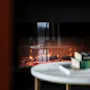 A cozy fireplace scene at Home Hotel Grand Bodø, with a table and books in the foreground, creating a warm ambiance.