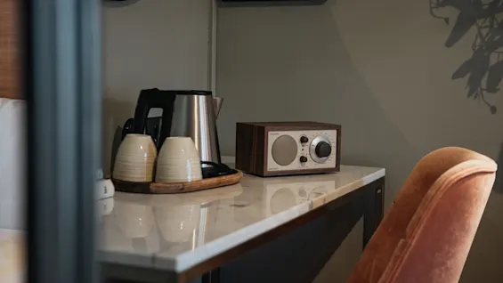 Et varmt og indbydende rum med en station til varme drikke med kedel og kopper, samt en klassisk radio til underholdning.