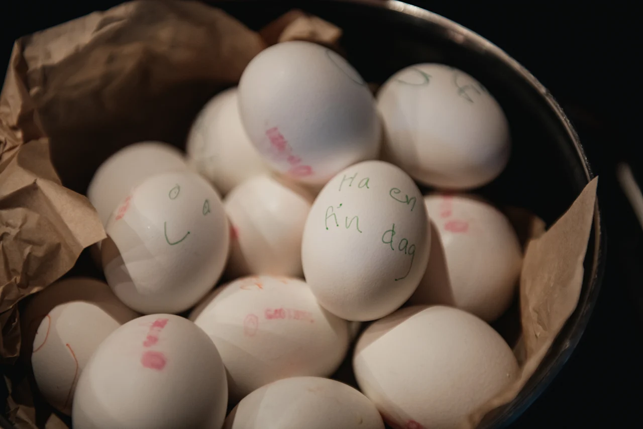 A bowl of white eggs, some with handwritten messages like 'Ha en fin dag' and a smiley face, at Home Hotel Uppsala.